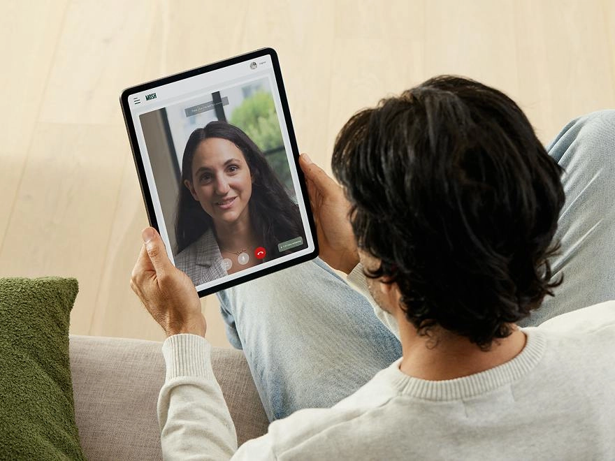 Man on the sofa on a video consult with a practitioner on a tablet